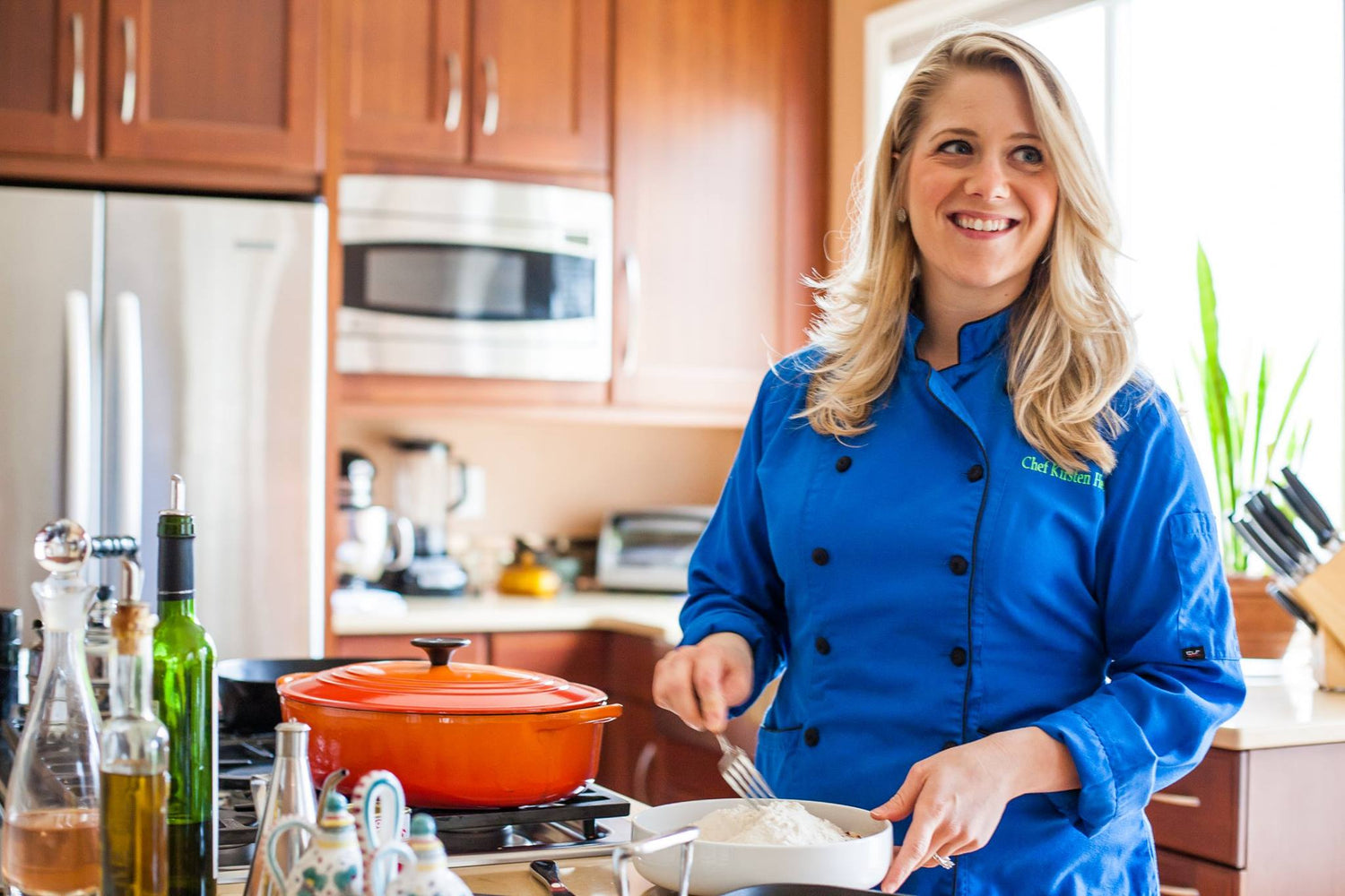 Chef Kirsten Sandoval in a blue chef coat, smiling